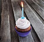 Tasty birthday cupcake with candle on wooden table