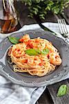Plate of fresh spaghetti with prawns and tomatoes on wooden table