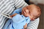 Newborn baby boy in parent's arms with thermometer