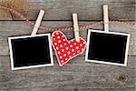 Two blank instant photos and red heart hanging. On wooden background