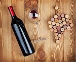 Red wine bottle, glass and grape shaped corks on wooden table background