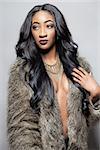 Beautiful black woman with long curly hair wearing a fur coat
