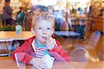 cute little boy enjoying ice cream in cafe, view from outside