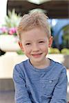 cute smiling little boy in blue shirt outside