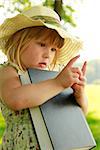 a beautiful little girl with the Book in nature