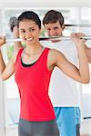 Portrait of a fit young man and woman lifting barbells in the gym