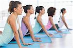 Side view of a fit class doing the cobra pose in a bright fitness studio