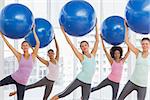 Happy fitness class and instructor doing pilates exercise with fitness balls in bright room