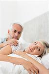 Woman ignoring mature man while lying in bed at the home