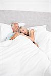 Loving mature man and woman lying in bed at the home