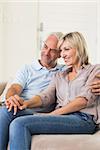 Side view of a smiling mature couple sitting on sofa at home