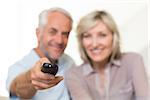 Blurred happy mature couple watching tv on sofa at home