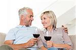 Portrait of a smiling mature couple with wine glasses sitting on sofa at home