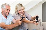 Portrait of a cheerful mature couple playing video game on sofa at home