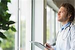 Thoughtful male doctor with clipboard in hospital