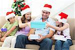 Smiling family exchanging Christmas gifts at home