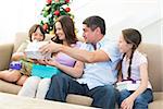 Happy family exchanging Christmas presents at home