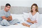 Portrait of unhappy couple sitting arms crossed in bed