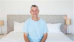 Portrait of senior man sitting on bed at home