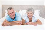 Portrait of happy senior couple lying in bed at home