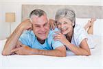 Portrait of loving senior couple lying in bed at home