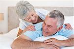 Happy senior couple lying in bed at home