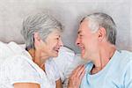 Smiling senior couple looking at each other in bed
