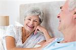 Portrait of happy senior woman with man in bed at home