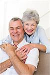 Portrait of happy senior woman embracing husband in house