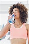 Fit young female drinking water at a bright gym