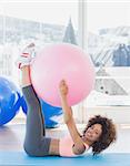 Side view of a sporty young woman with exercise ball in the fitness studio