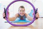 Portrait of a smiling sporty young woman with exercising ring in fitness studio