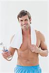 Portrait of a smiling shirtless man holding water bottle over white background
