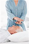 Female therapist performing Reiki over forehead of senior man at health spa
