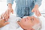 Senior man having Reiki treatment by massage therapist at spa