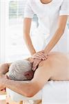 Female physiotherapist massaging back of senior patient in clinic