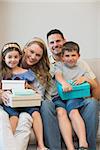 Portrait of happy family with presents sitting on sofa at home