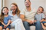 Happy parents and children sitting on sofa at home