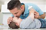 Loving father kissing baby boy on forehead at kitchen counter