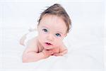 Adorable baby boy with blue eyes looking away in bed