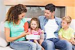 Happy family sitting on sofa celebrating a birthday at home in living room