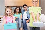 Siblings showing presents in front of parents on the couch at home in living room