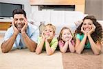 Happy siblings lying on the rug posing with their parents at home in living room