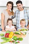 Happy family preparing vegetables together at home in kitchen