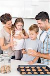 Cheerful family having cookies and milk at home in kitchen