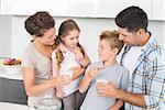 Happy family having cookies and milk at home in kitchen
