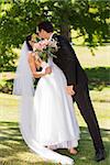 Full length of a romantic newlywed couple kissing in the park