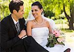 Smiling young newlywed couple sitting in the park