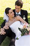 Happy young newlywed couple sitting in the park