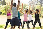 Instructor with group of fitness class exercising in the park